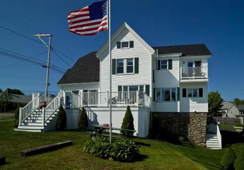 a white house with an american flag in front of it at Main House at One Long Beach in York Beach
