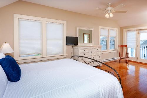 a bedroom with a bed and a tv and windows at Main House at One Long Beach in York Beach