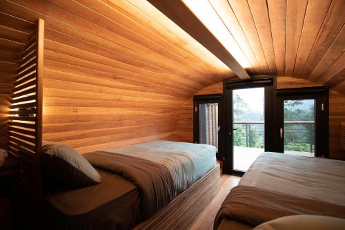 two beds in a room with wooden walls at The Rock Lodge in Ban Nahin-Nai (1)