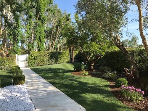a garden with green grass and trees and a walkway at Beautiful Modern Villa in Albarella by Beahost in Isola Albarella