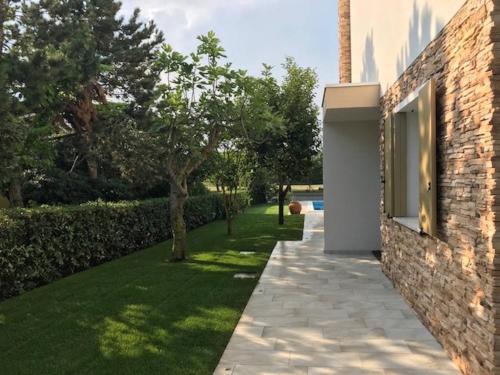 a garden with a stone walkway next to a building at Beautiful Modern Villa in Albarella by Beahost in Isola Albarella