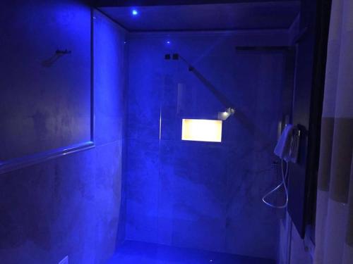 a blue bathroom with a shower with a glass door at Beautiful Modern Villa in Albarella by Beahost in Isola Albarella