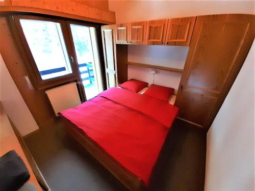 uma cama vermelha num pequeno quarto com uma janela em Zinal - Studio/mezzanine à 2 pas du télécabine em Zinal