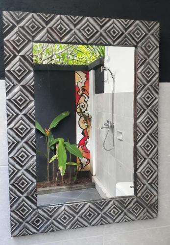 a bathroom mirror with a painting on the wall at Indah Homestay and Cooking classes in Senggigi