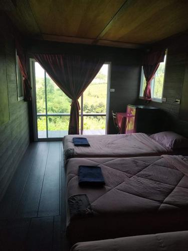 a bedroom with two beds in a room with windows at เขาค้อ อันนาอิม รีสอร์ท in Ban Thung Samoe