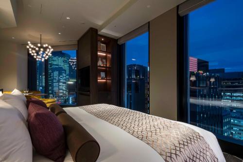 a bedroom with a large window with a city skyline at Hotel GrandBach Tokyo Ginza in Tokyo