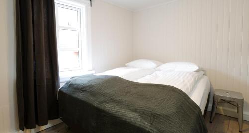 a bedroom with a bed with white sheets and a window at Old Charm Reykjavik Apartments in Reykjavík