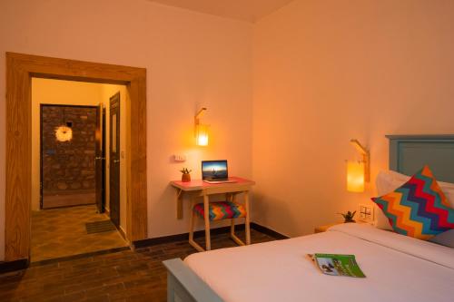 a bedroom with a bed and a desk with a laptop at goSTOPS Dehradun, Maldevta in Dehradun