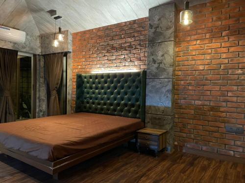 Cold Spot Village Resort في ماهاباليشوار: غرفة نوم بحائط من الطوب وسرير