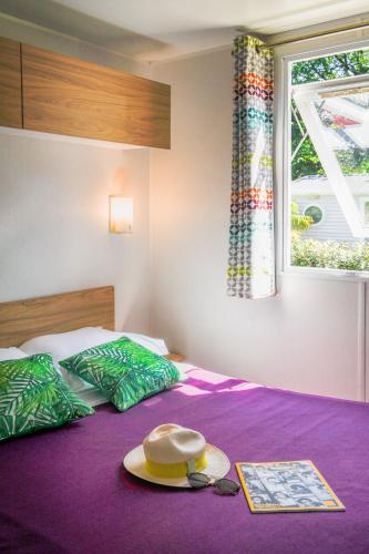 un chapeau et des lunettes de soleil sur un lit avec une fenêtre dans l'établissement Camping Erreka, à Bidart