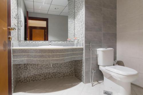 a bathroom with a toilet and a sink and a mirror at Luxury 1 BR Beach Apartment with Full Sea View in Ajman 