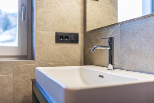 a bathroom sink with a faucet and a mirror at Apartments Armeri Blue Dolomites in San Vigilio Di Marebbe