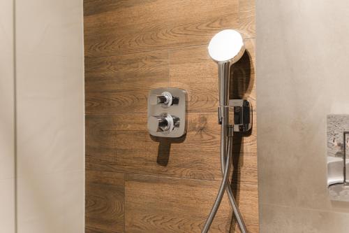 a shower in a bathroom with a wooden wall at Royal Apartments & Spa Zakopane-Cyrhla in Zakopane