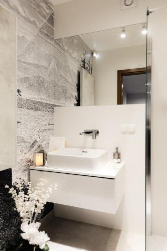 a white bathroom with a sink and a mirror at Royal Apartments & Spa Zakopane-Cyrhla in Zakopane