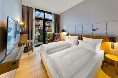 een hotelkamer met een groot bed en een televisie bij Unique by ATLANTIC Hotels Bremen in Bremen