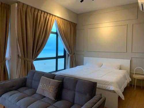 a bedroom with a bed and a couch and a window at Kuantan Seaview Studio@Imperium Residence TgLumpur in Kuantan