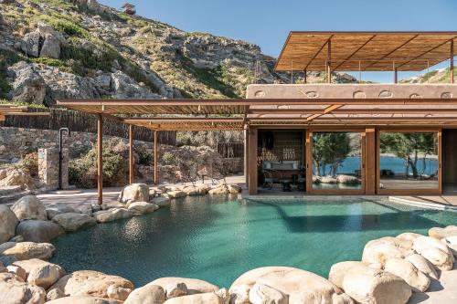 a house with a pool of water with rocks at Elafonisi Villas in Livadia