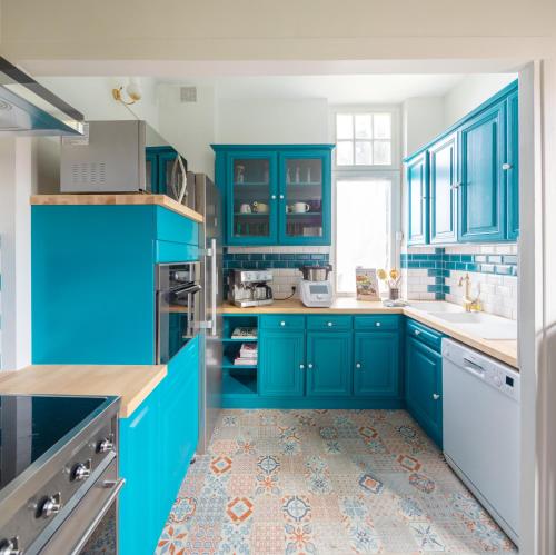 une cuisine bleue avec des appareils électroménagers blancs et des armoires bleues dans l'établissement La Maison de Florence, à Angers