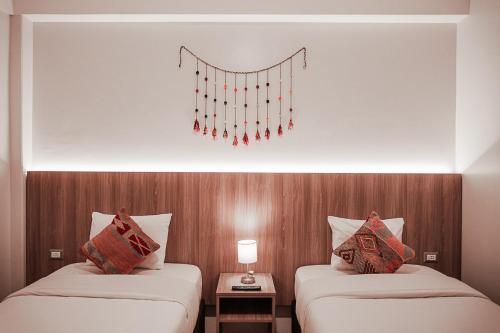 two beds in a hotel room with a chandelier at Casa Matara Boutique in Cusco