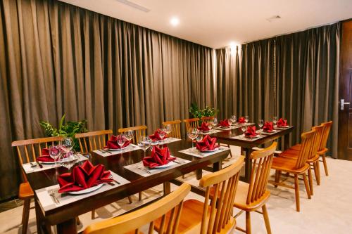 a dining room with long tables and chairs with red bows at Songlam Waterfront Hotel - 藍江酒店 in Ha Tinh