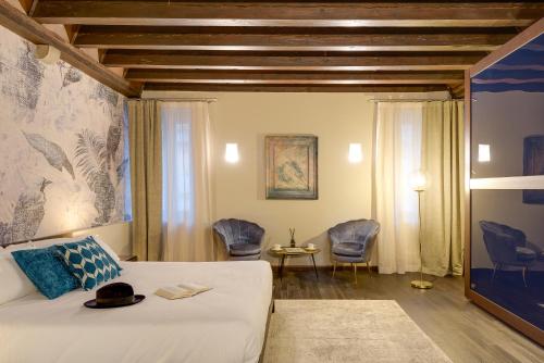a hotel room with a bed and chairs in it at PALAZZO DUOMO Suites in Udine Center in Udine
