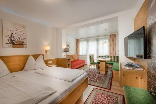 バート・ホーフガシュタインにあるPension Mariaのベッドとリビングルームが備わるホテルルームです。