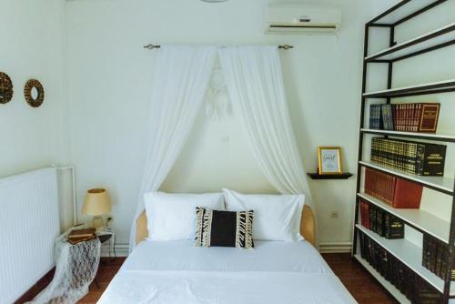 a bedroom with a white bed with a book shelf at Akadimia Luxury Apartment in Mytilene