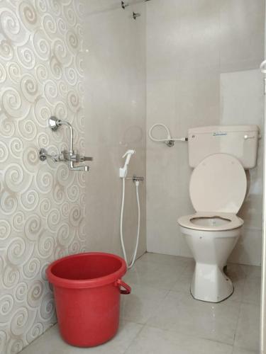 a bathroom with a toilet and a red bucket at Megha Resort , Hampi in Hampi