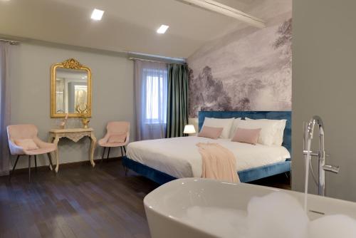 um quarto de hotel com uma cama e uma banheira em PALAZZO DUOMO Suites in Udine Center em Udine