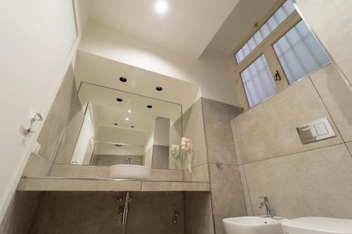La salle de bains est pourvue d'un lavabo et d'un miroir. dans l'établissement Le 4 Stagioni Dante H Napoli Centro, by ClaPa Group, à Naples
