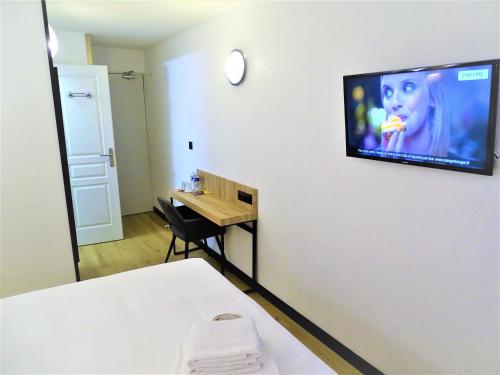 a room with a bed and a television on a wall at Euro Hôtel Paris Créteil in Créteil
