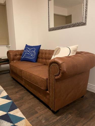a brown leather couch sitting in a living room with a mirror at A luxurious 2-Bedroom flat in Rugby. in Rugby