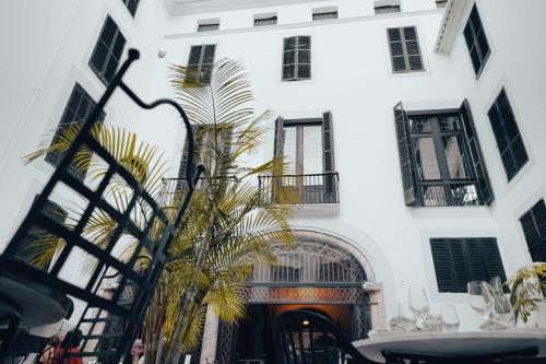 a white building with a palm tree in front of it at Hotel Born in Palma de Mallorca