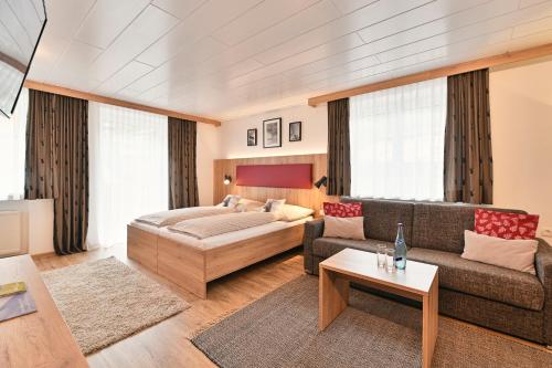 a living room with a bed and a couch at Haus Flexen Appartements & Suite in Stuben am Arlberg
