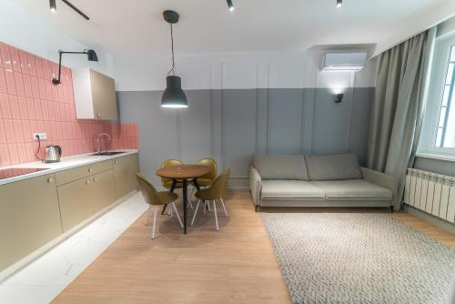 eine Küche und ein Wohnzimmer mit einem Sofa und einem Tisch in der Unterkunft Manica R-House in Almaty