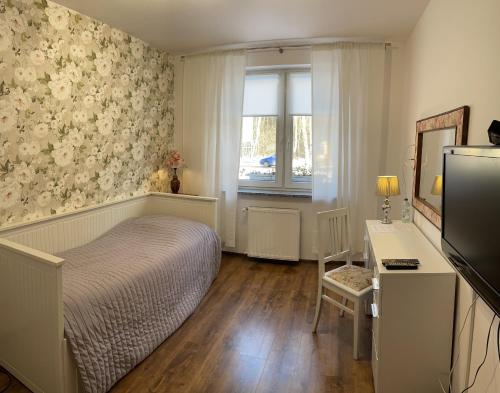 a bedroom with a bed and a desk and a window at Gosciniec Pod Brzozami in Poznań