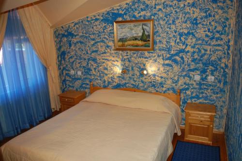 a bedroom with blue wallpaper with a bed and a picture at COMPLEX HARMONY/КОМПЛЕКС ХАРМОНИЯ in Tryavna