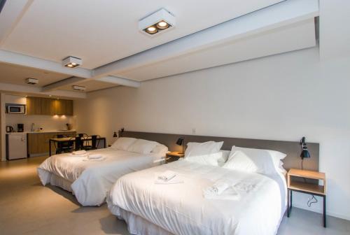 two beds with white sheets in a room at Austral Departamentos in Ushuaia