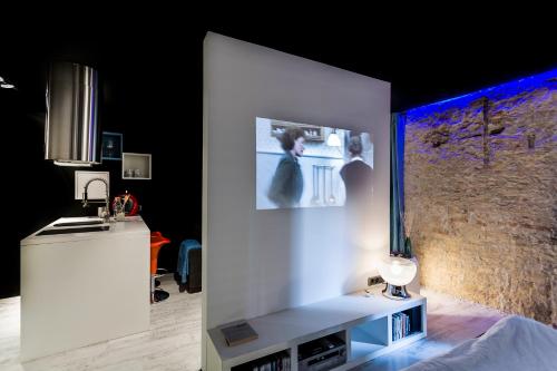 a room with a white wall with a tv on it at Zrooms&Suites Hostel Boutique in Zaragoza
