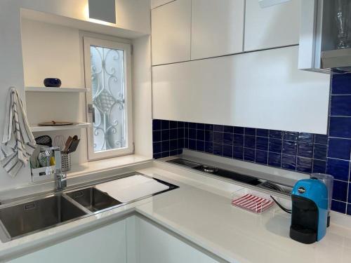 a white kitchen with a sink and a window at Le Rocce da Tragara, Tragara essential in Capri