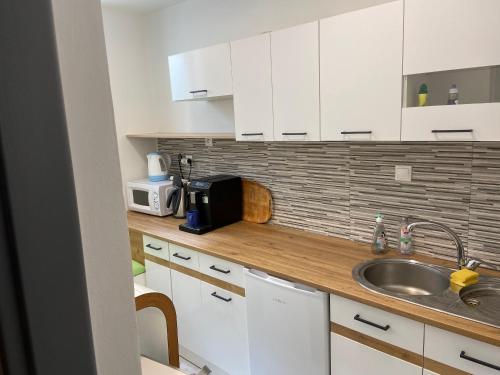 a kitchen with white cabinets and a sink and a microwave at Stylové ubytování v historickém centru Litomyšle in Litomyšl