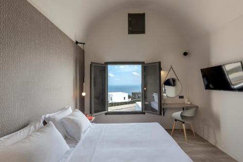 a bedroom with a white bed and a window at Pearl Inn Hotel by Pearl Hotel Collection in Imerovigli