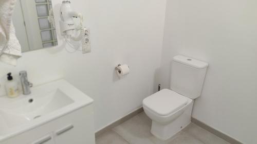 a white bathroom with a toilet and a sink at valencialoft in Valencia