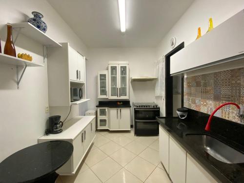 een keuken met witte kasten en zwarte aanrechtbladen bij Apartamento Mar da Praia da Costa in Vila Velha