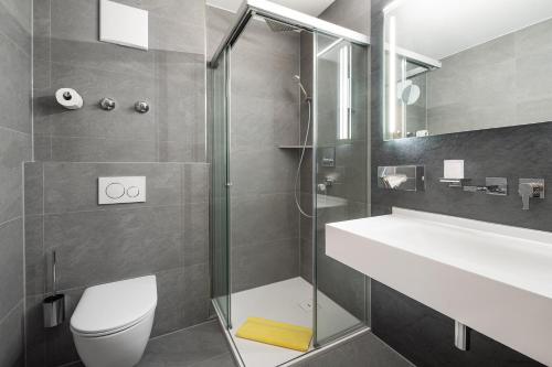 a bathroom with a shower and a toilet and a sink at Hotel Neuwirt in Hallbergmoos
