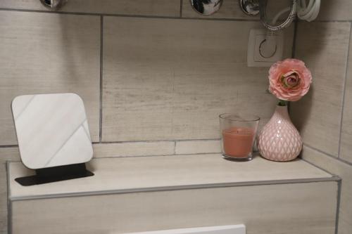 a flower in a vase and a glass of water on a shelf at Kuća za odmor GUSKA in Kopačevo
