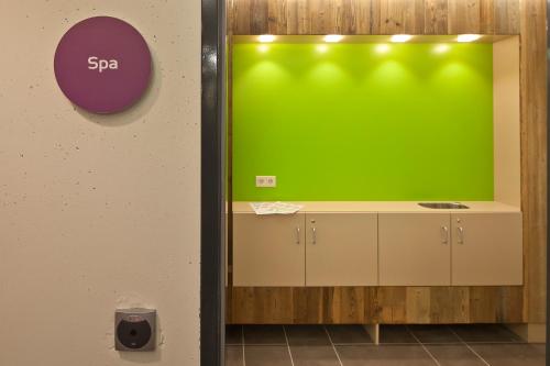 a green wall in a bathroom with a counter at Explorer Hotel Neuschwanstein in Nesselwang