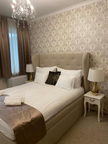 ブダペストにあるVáralja Homeのベッドルーム(シャンデリア付きの白い大型ベッド1台付)