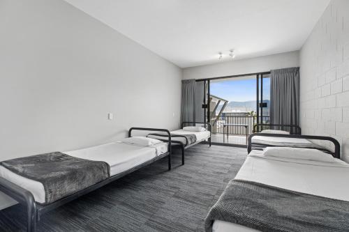 three beds in a room with a balcony at Gilligan's Hotel & Resort Cairns in Cairns
