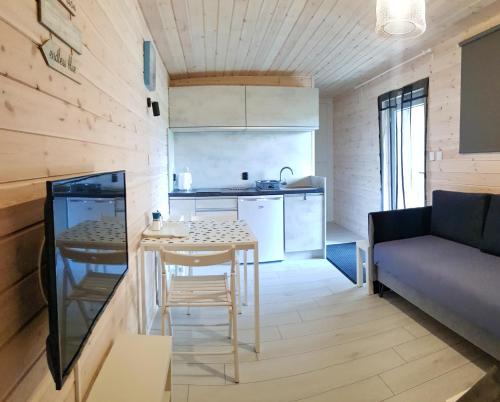 a small kitchen and living room with a table and a couch at Bungalow Mila Morska in Junoszyno